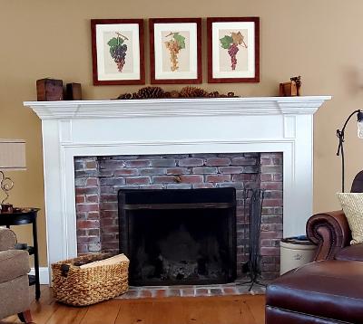 a decorative set of 3 framed antique wine prints, lithographs over 100 years old, of wine grapes, placed over a fireplace.